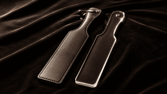 narrow rigid paddle on dark surface suited for sharp sting sensation impact play