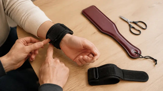 Couple discusses bondage readiness beside paddle and padded cuffs