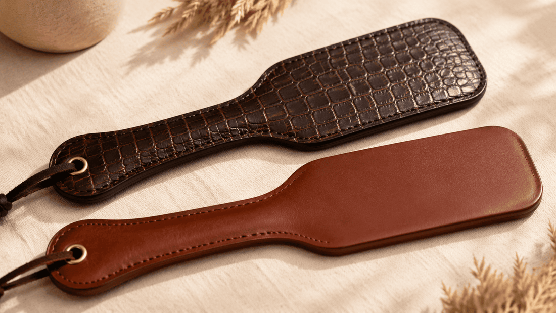textured python embossed leather paddle beside smooth flat leather paddle on dark surface