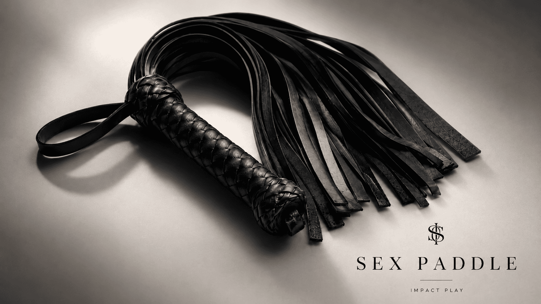 black leather flogger with multiple tails in dramatic studio lighting