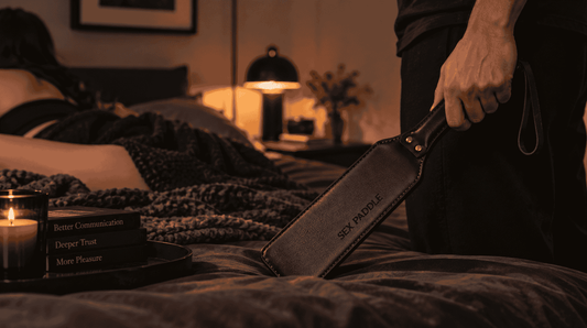 Top holding a leather spanking paddle while learning impact play control, communication, and safe force calibration