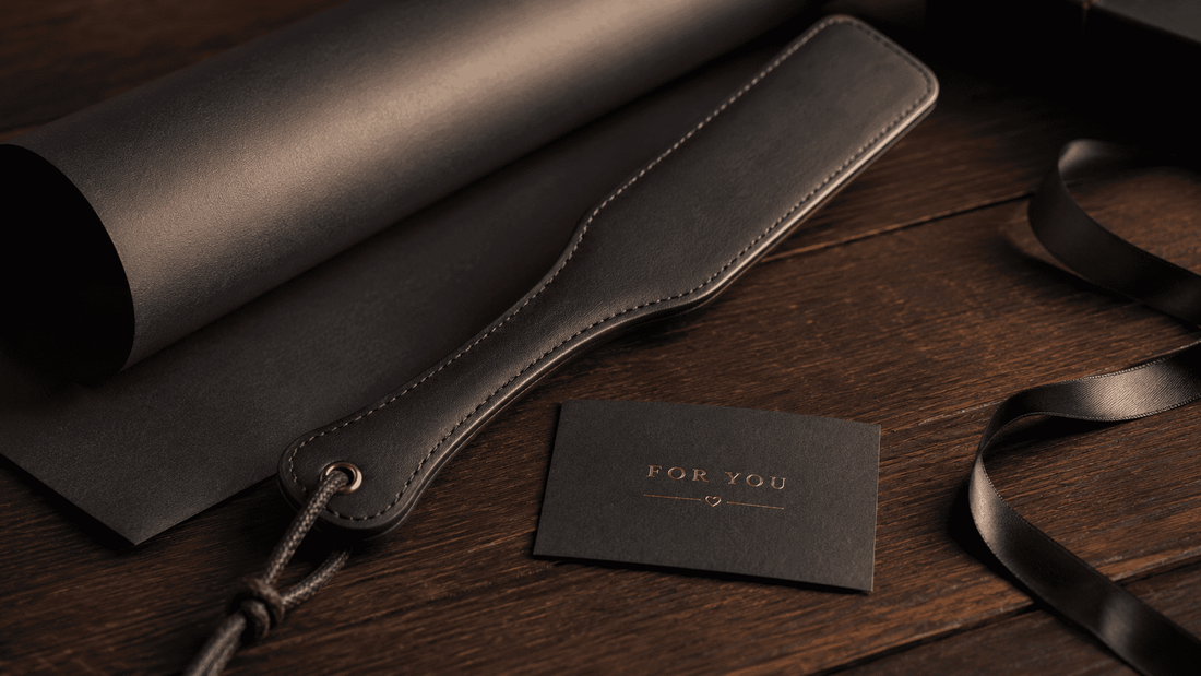 leather paddle beside simple dark gift wrapping and card on wooden surface