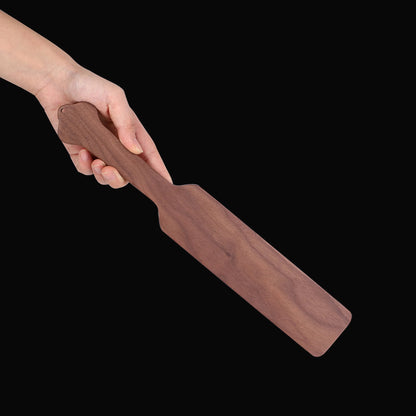Wooden paddle from 5-piece solid wood spanking set held in hand