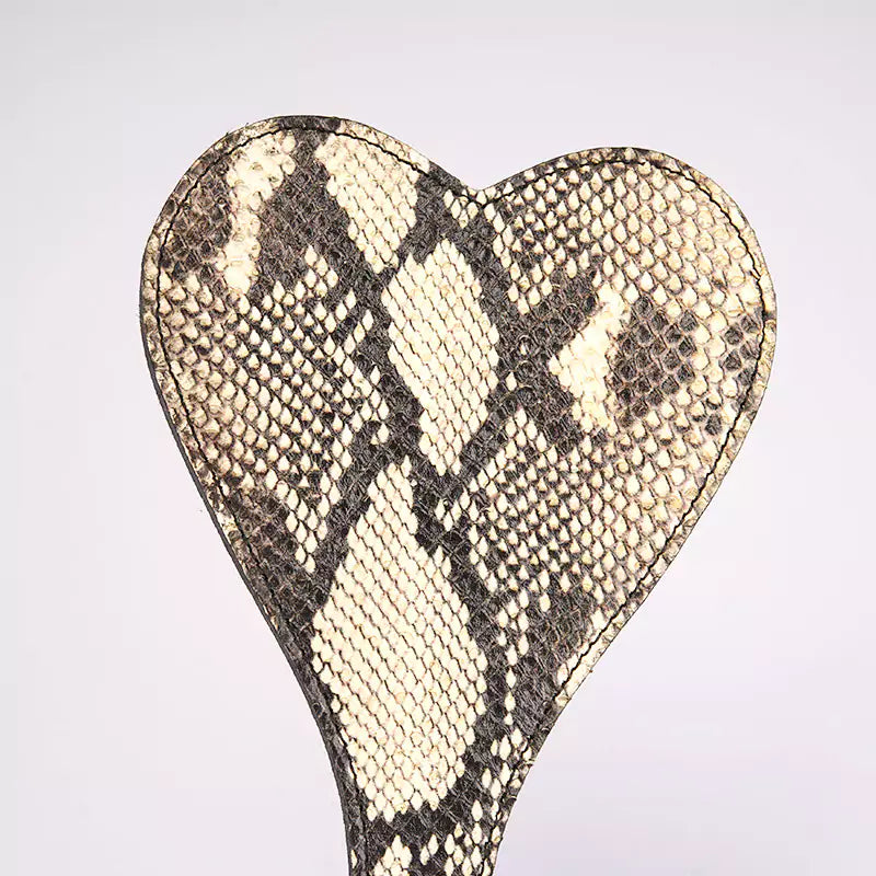 Detail view of the beige snake-pattern paddle’s heart-shaped outline