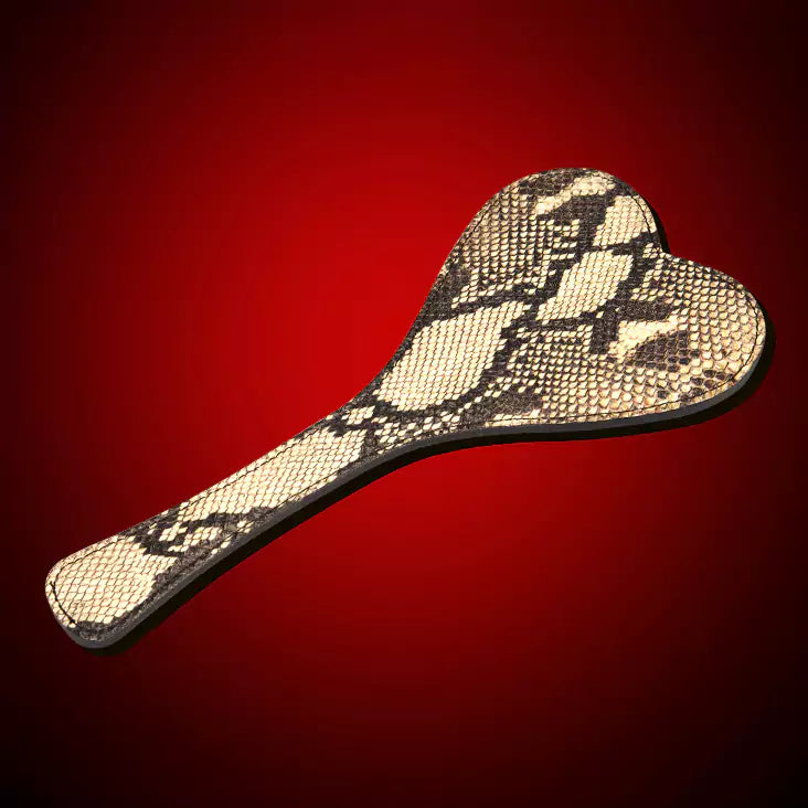 Beige snake-pattern heart paddle in a styled product setting