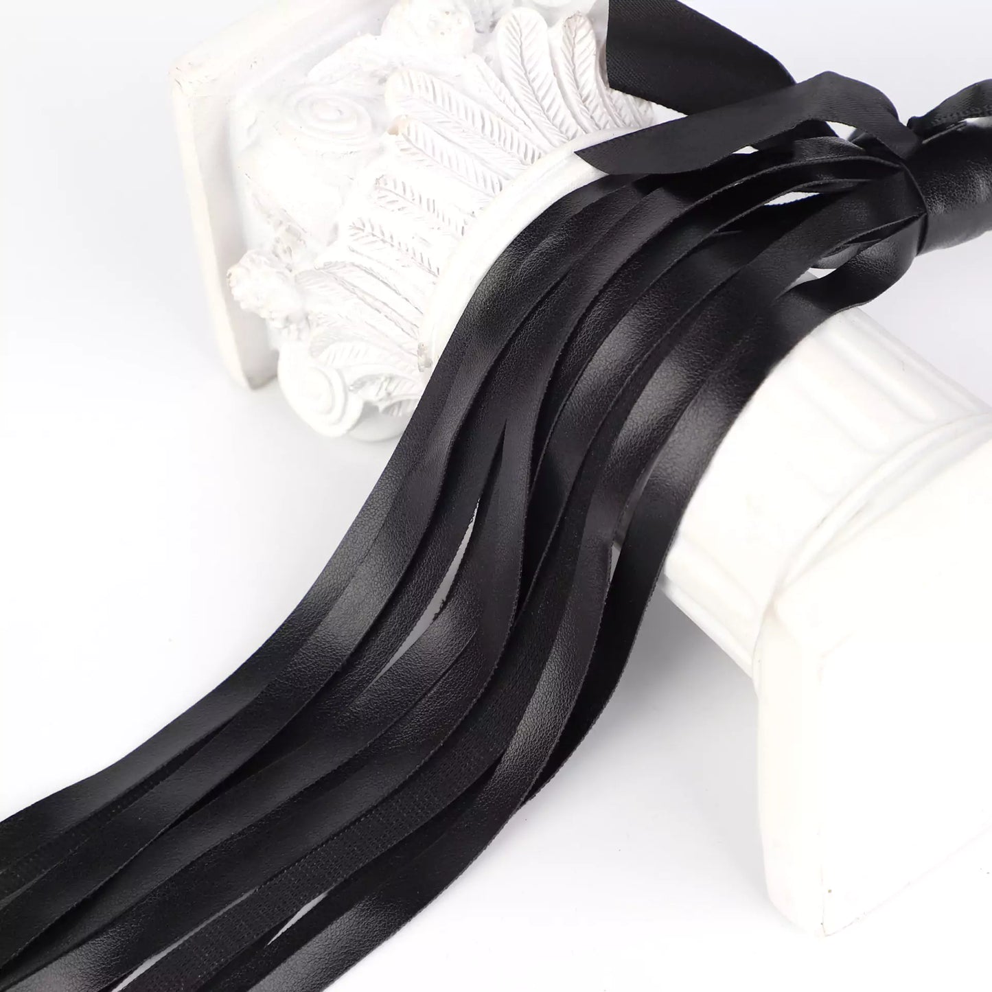 Close-up of black faux leather fringe with satin bow detail