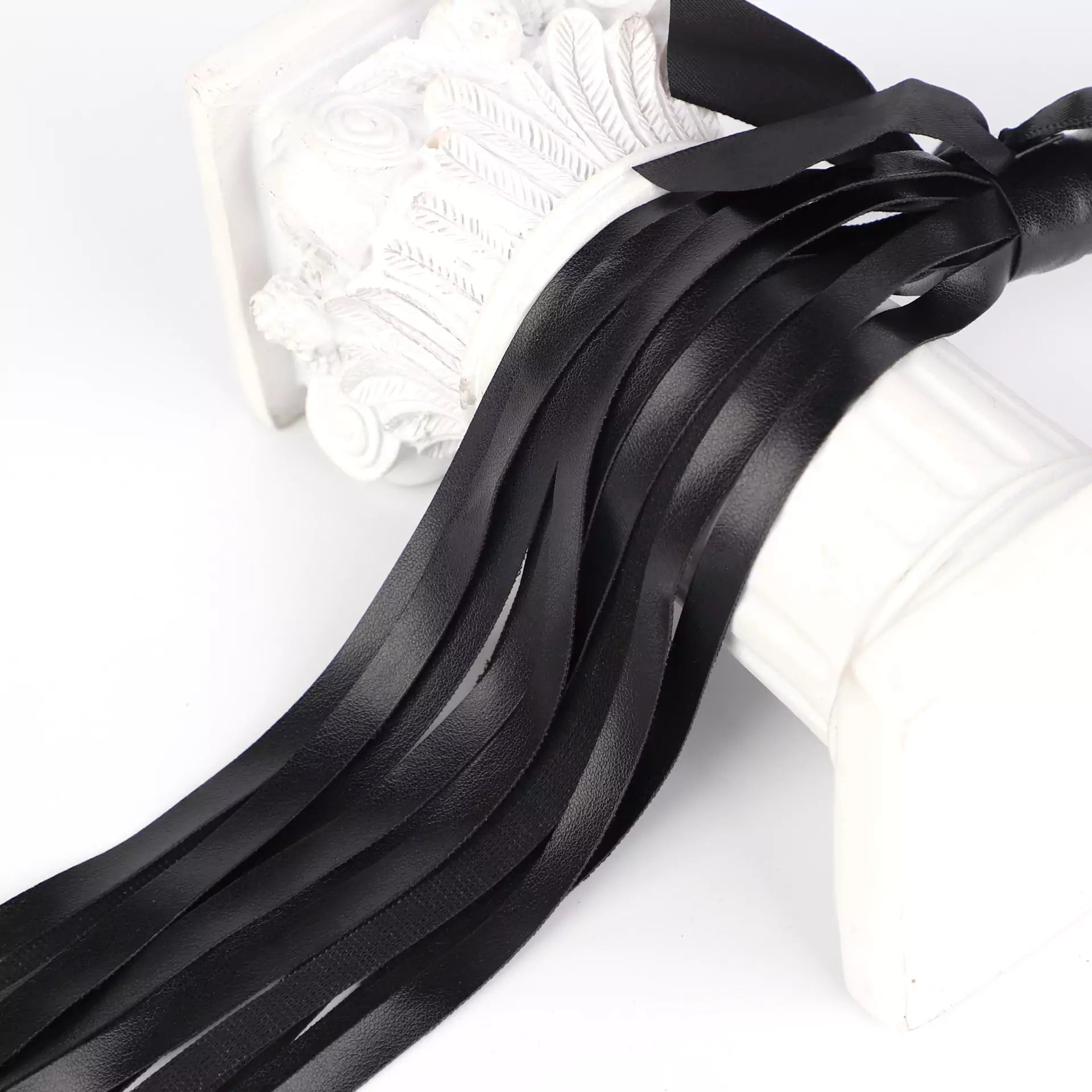 Close-up of black faux leather fringe with satin bow detail