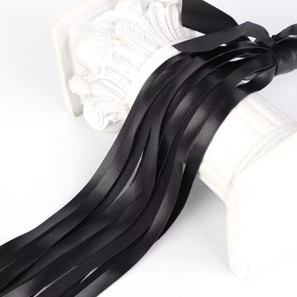 Close-up of black faux leather fringe with satin bow detail