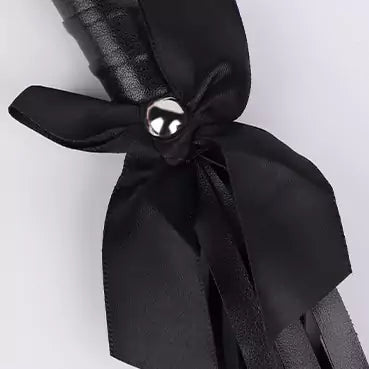 Black flogger handle with satin bow and pearl accent close-up