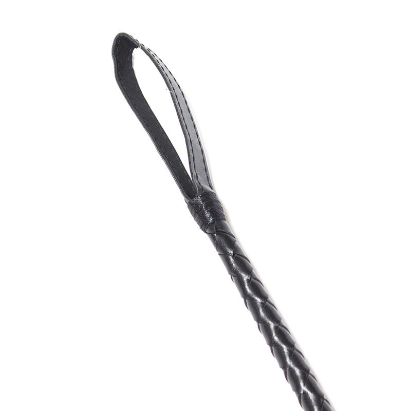Close-up of faux leather striking tip on black lace riding crop