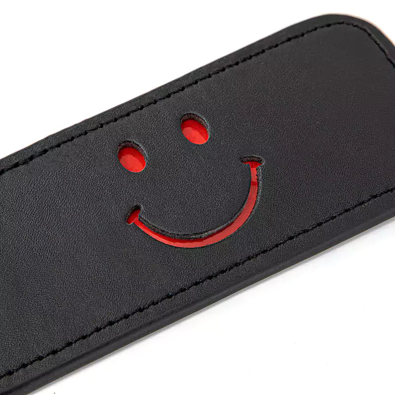 Close-up of red cut-out smiley face on faux leather paddle