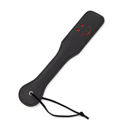 Black smiley leather spanking paddle full view under studio lighting