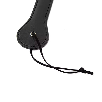 Wrist strap detail on black smiley spanking paddle