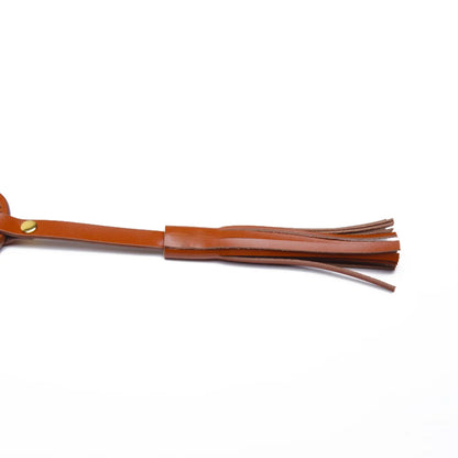Tassel and strap detail on leather spanking paddle