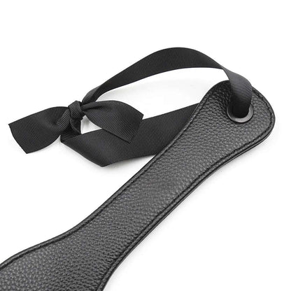 Ribbon-style wrist strap detail on black discipline paddle