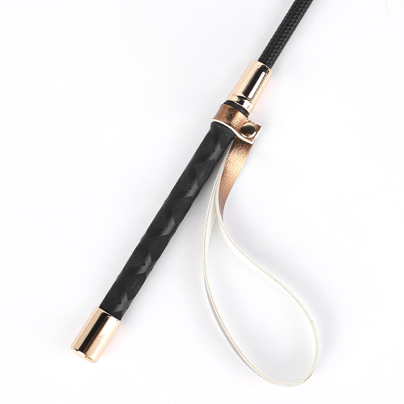 Close-up of handle and hanging loop on gold and silver metallic riding crops