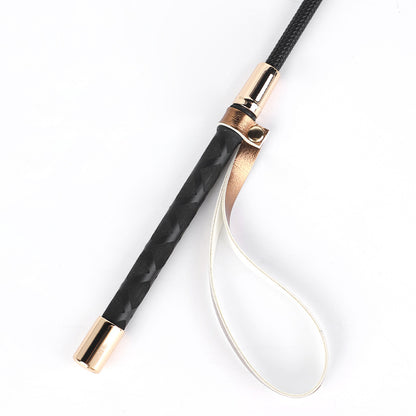 Close-up of handle and hanging loop on gold and silver metallic riding crops