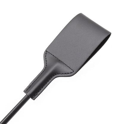 Close-up of leather riding crop striking surface back with stitching detail