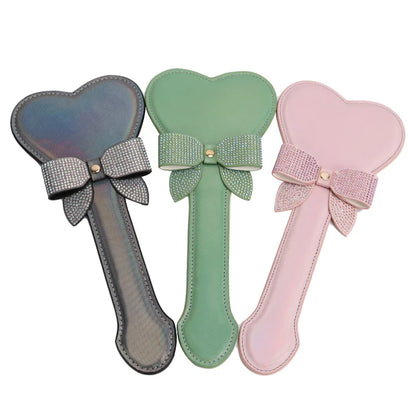 Black pink and green iridescent heart-shaped spanking paddles grouped full view