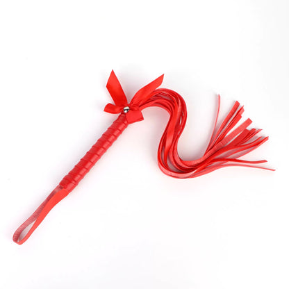 Red bow-tie fringe BDSM flogger full view under neutral lighting