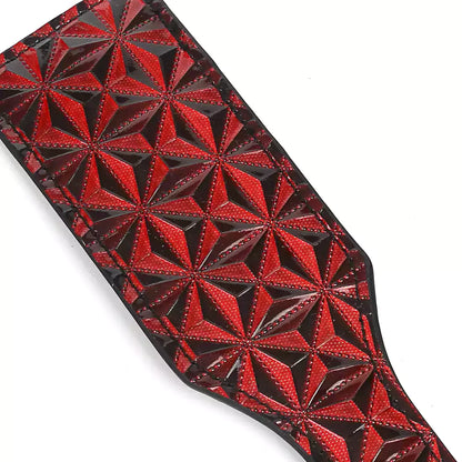Full view of red diamond-textured paddle face on faux leather paddle