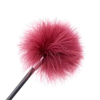 Close-up of soft feather tip on red feather teasing BDSM crop