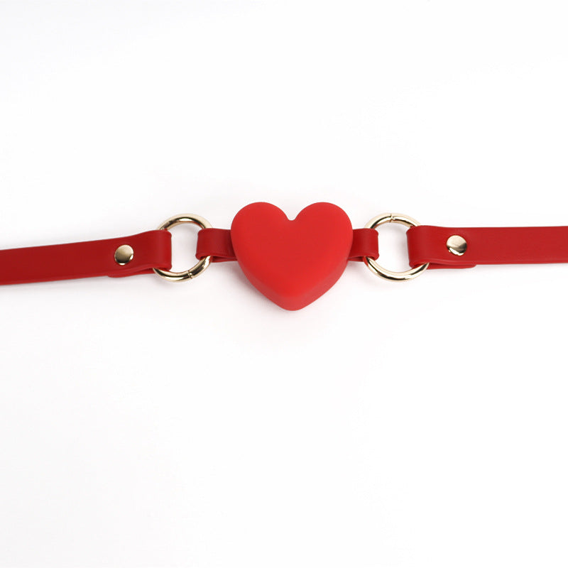 Close-up detail of the red heart-shaped silicone ball gag with wide strap