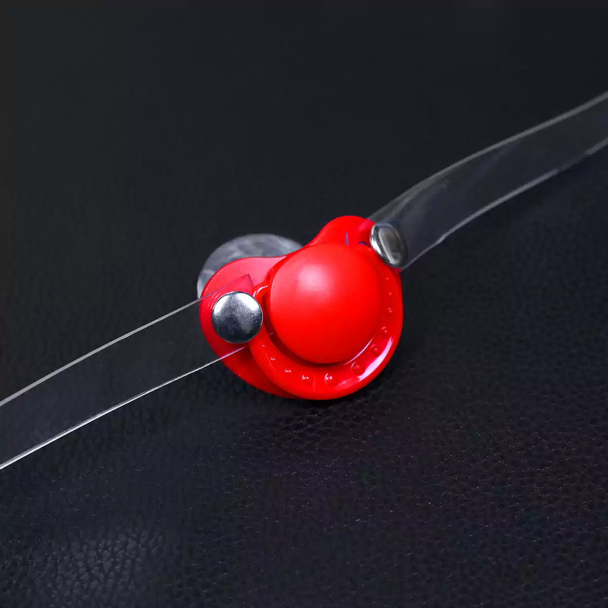 Close-up detail of the silicone pacifier restraint gag and clear PVC strap