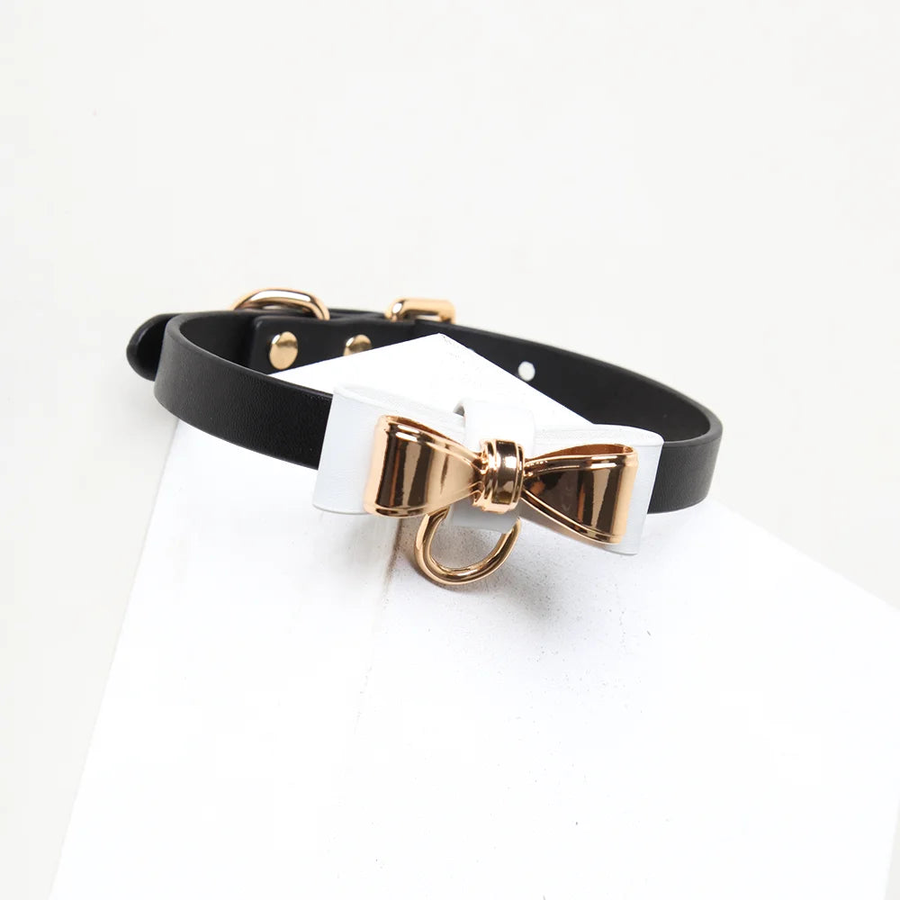 White bow and gold hardware detail on black strap collar